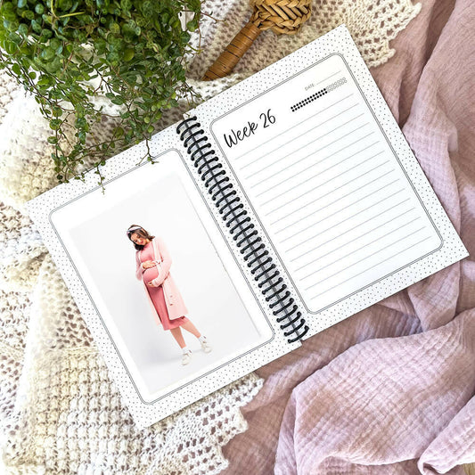 Bump to Bubba pregnancy journal open to week 26 pages flat lay with pregnant lady and plant in background, by Paper Heart Design