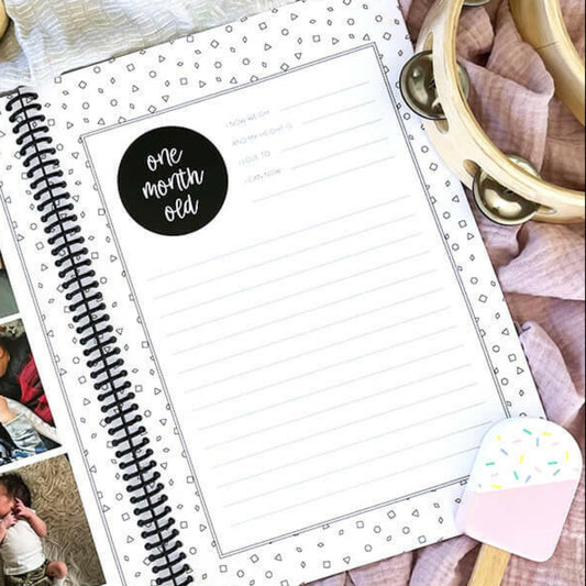 Hey Baby baby milestone book open to monthly milestone pages - first year memory book by Paper Heart Design