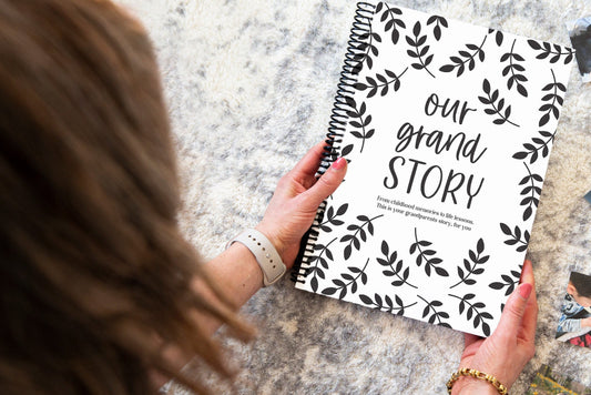 Our Grand Story grandparent keepsake book held by brunette woman over grey rug, grandparent memory book by Paper Heart Design NZ