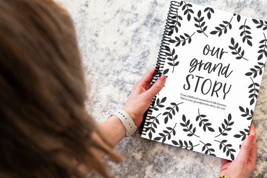 Our Grand Story grandparent keepsake book held by brunette woman over grey rug, grandparent memory book by Paper Heart Design NZ
