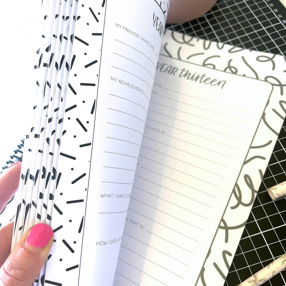 School Record Book open to year thirteen page and empty pocket, held open by female hand with pink nails, school years keepsake by Paper Heart Design NZ
