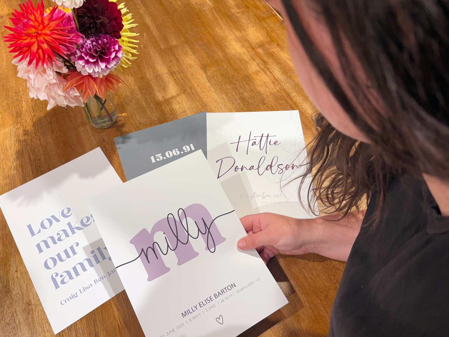 Custome personalized baby and family prints set against a wooden table with bright flowers in a vase