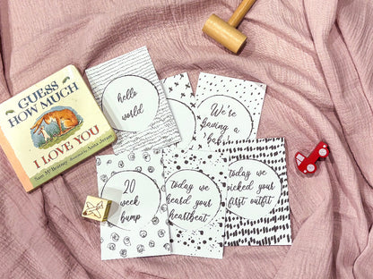 Downloadable bump milestone cards laid out on pink fabric with Guess How Much I Love You book and baby toys, printable pregnancy keepsake by Paper Heart Design