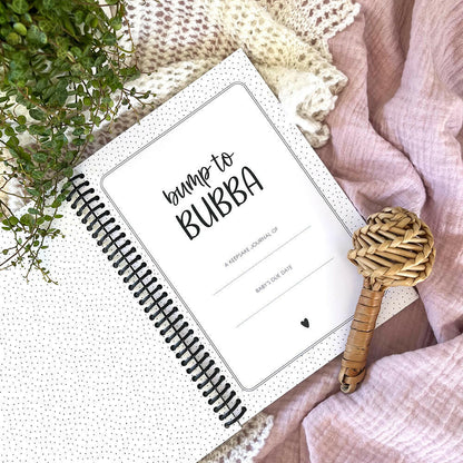 Bump to Bubba pregnancy keepsake journal close up of first page and title flat lay with rattle, pregnancy memory book by Paper Heart Design