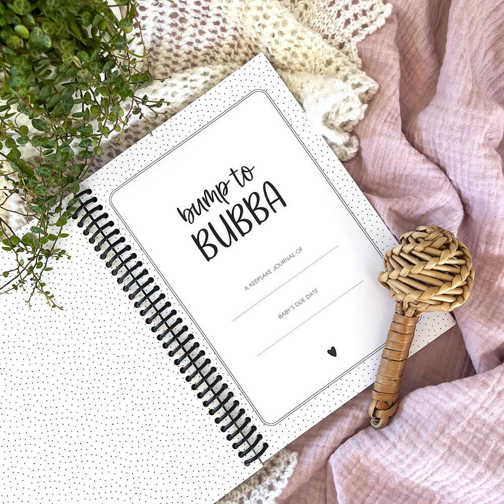 Bump to Bubba pregnancy keepsake journal close up of first page and title flat lay with rattle, pregnancy memory book by Paper Heart Design