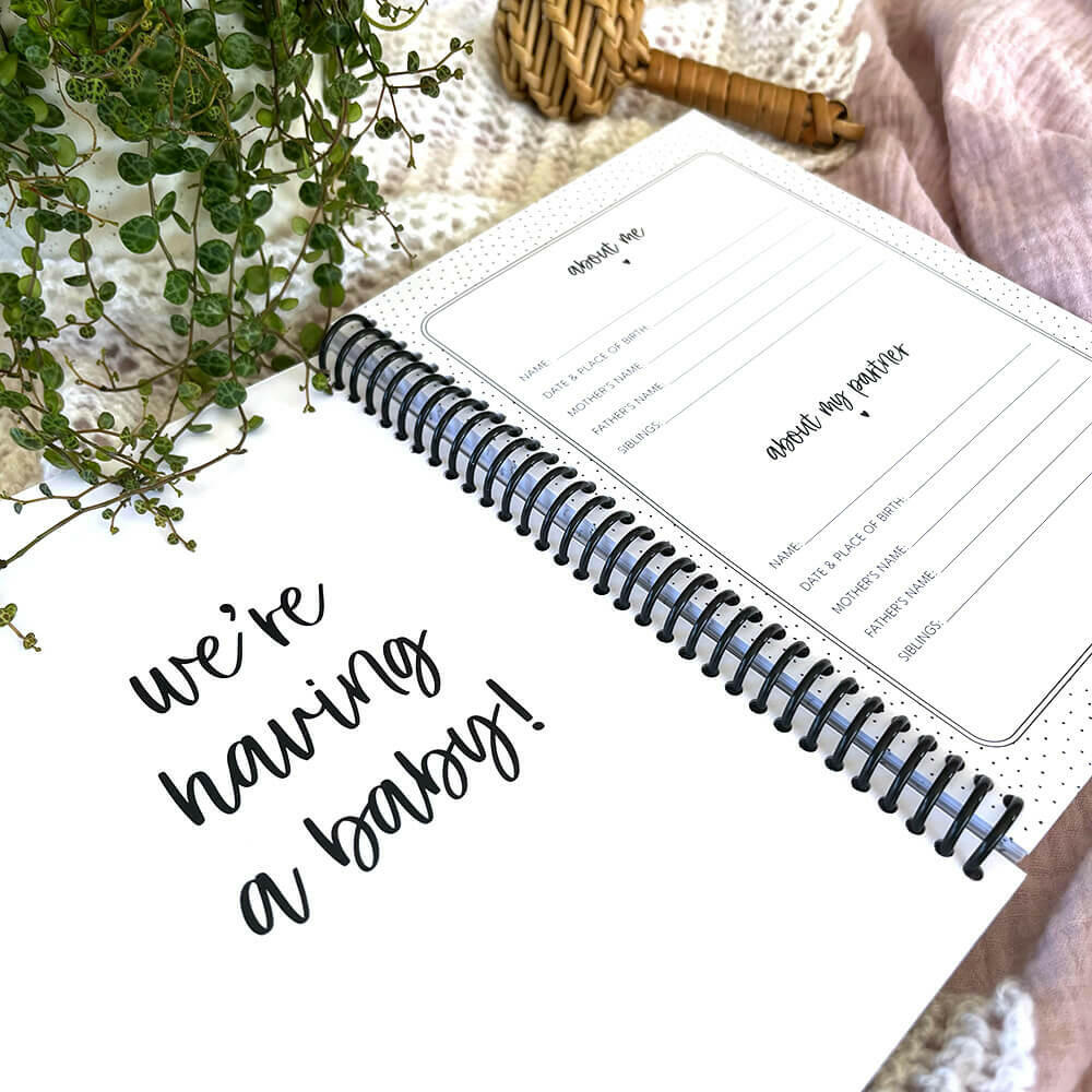 Bump to Bubba pregnancy keepsake journal open to We're Having a Baby and About Us pages with rattle, by Paper Heart Design