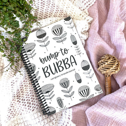 Bump to Bubba pregnancy journal styled flat lay with rattle and plant, NZ pregnancy memory book by Paper Heart Design