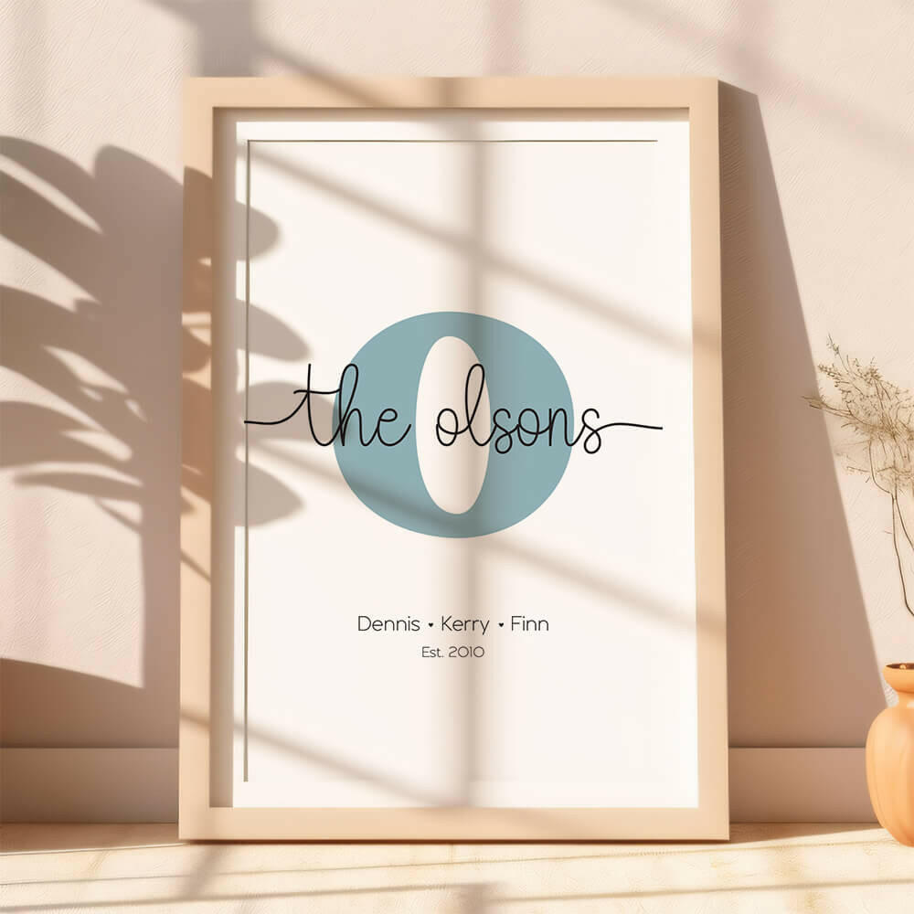Family Script personalised family name print with cornflower serif initial and black script font, lifestyle image with plant shadows, by Paper Heart Design