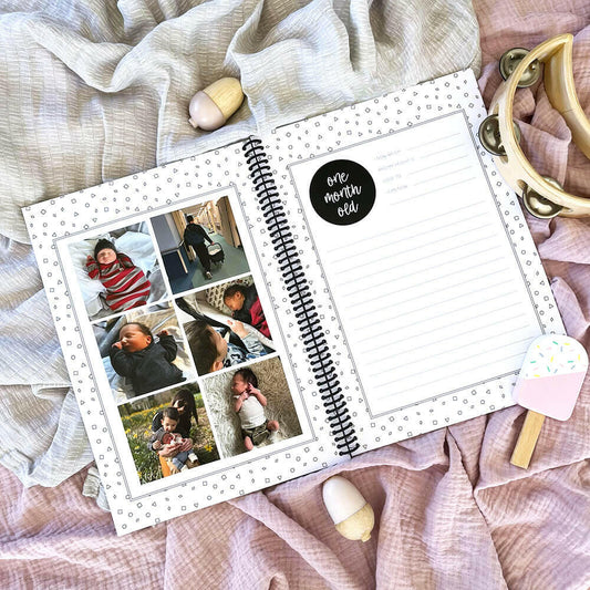Hey Baby baby milestone book open to monthly milestone pages - first year memory book by Paper Heart Design