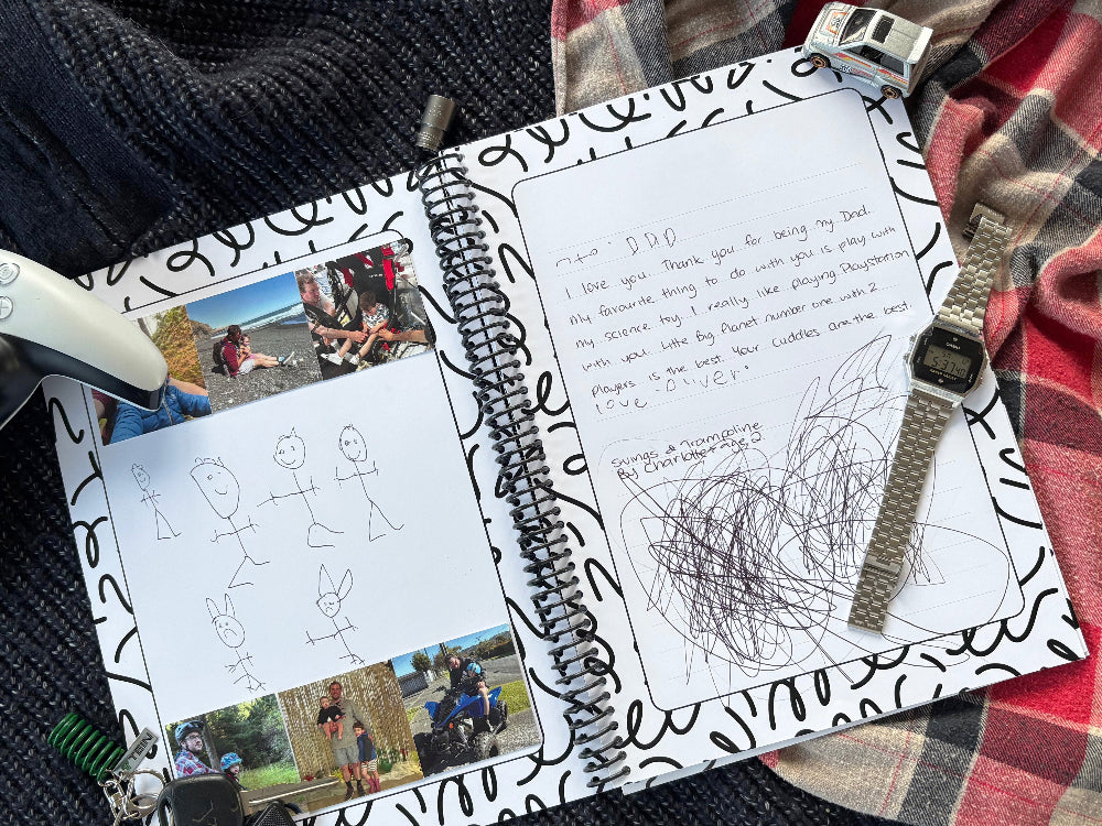 Letters to Dad keepsake book open to filled inner pages showing photos, child's stick family drawing and note to Dad on navy knit and red plaid background with toy car, 10mm socket and Casio watch, by Paper Heart Design NZ