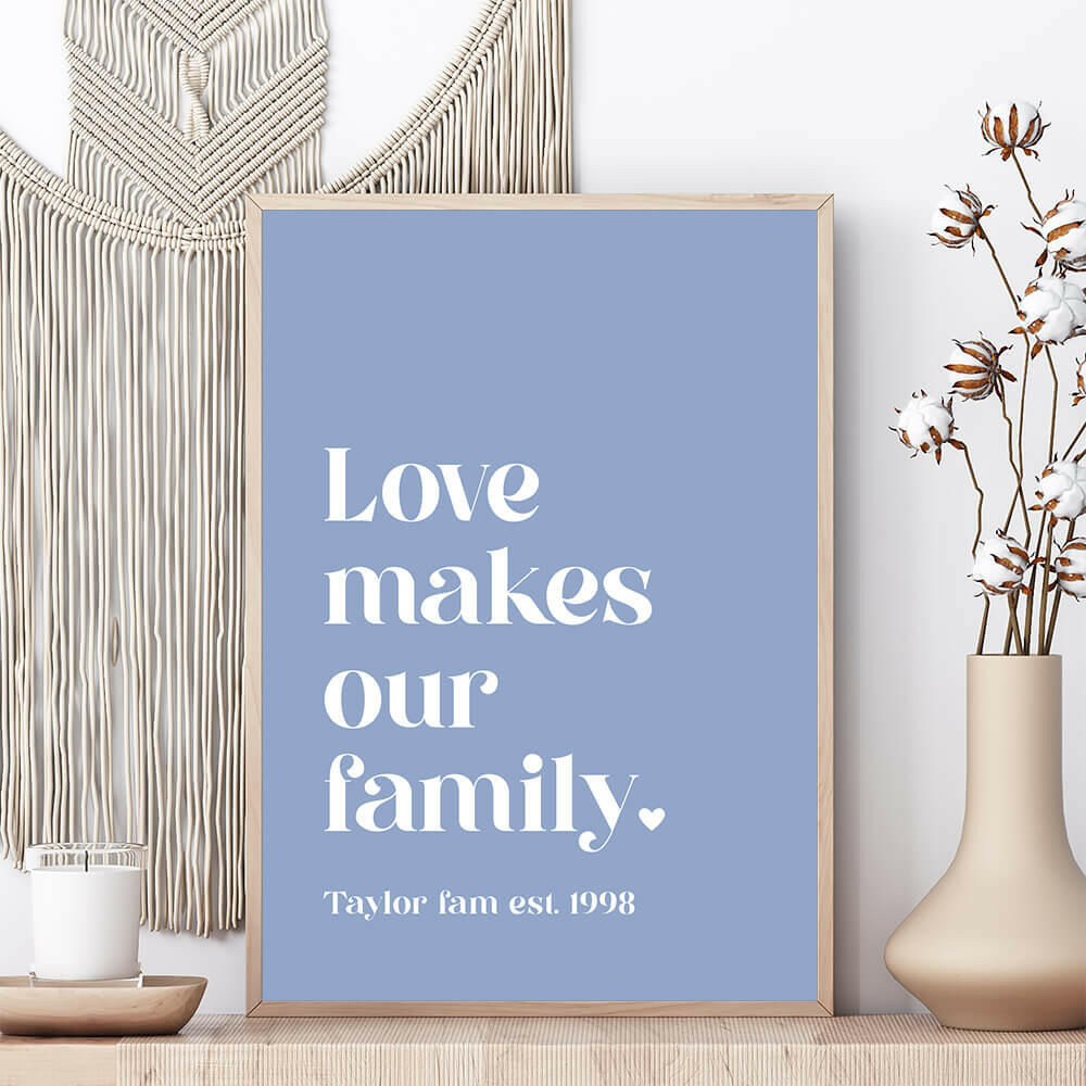Love Makes Our Family personalised family print in cornflower framed on shelf with vase beside and macrame wall hanging behind, by Paper Heart Design NZ