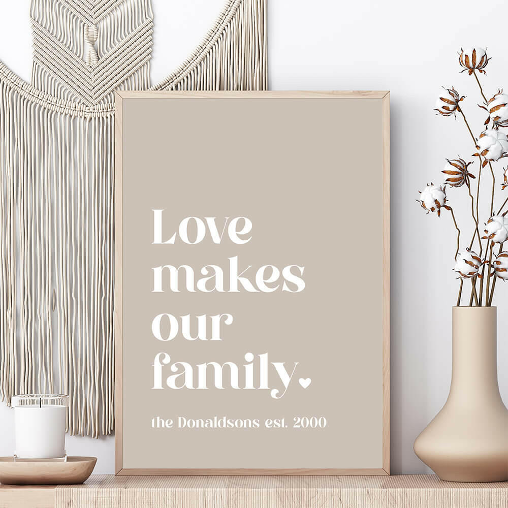 Love Makes Our Family personalised family print in pebble framed on shelf with vase and candle beside and macrame wall hanging behind, by Paper Heart Design NZ