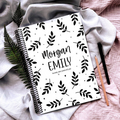 Personalised 21 Years Keepsake Book ferns cover flat lay on pink and grey fabric, with fern leaves, pencil and pen around, a custom birthday letter keepsake by Paper Heart Design NZ