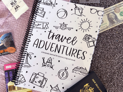 Travel Adventures keepsake journal front cover flat lay on pink and grey fabric with passport, tickets and US money, travel keepsake by Paper Heart Design NZ