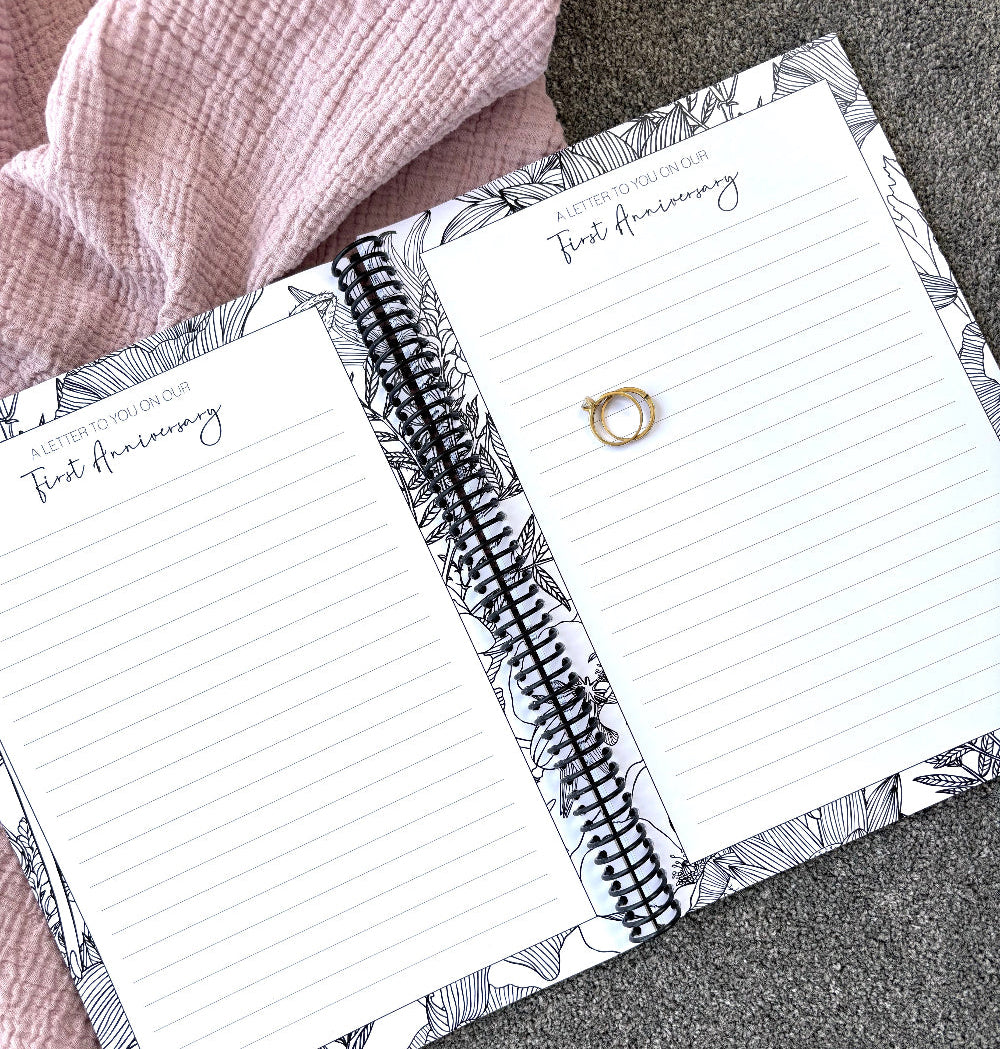 You and Me Anniversary keepsake book open to a letter to you on our first anniversary double page spread with gold rings on pink and grey fabric, by Paper Heart Design NZ