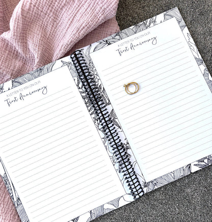 You and Me Anniversary keepsake book open to a letter to you on our first anniversary double page spread with gold rings on pink and grey fabric, by Paper Heart Design NZ