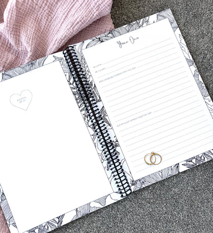 You and Me Anniversary keepsake book open to year one page spread with milestone prompts and photo space, gold rings on pink and grey fabric, by Paper Heart Design NZ